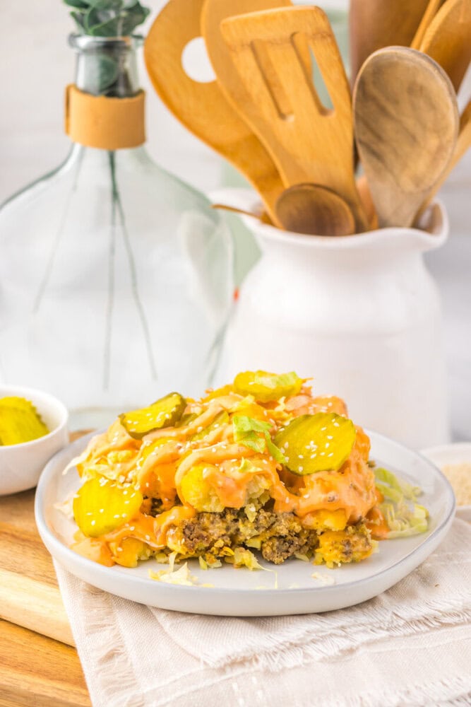 Slow cooker Big Mac tater tot casserole with ground beef, cheese, and pickles on white plate