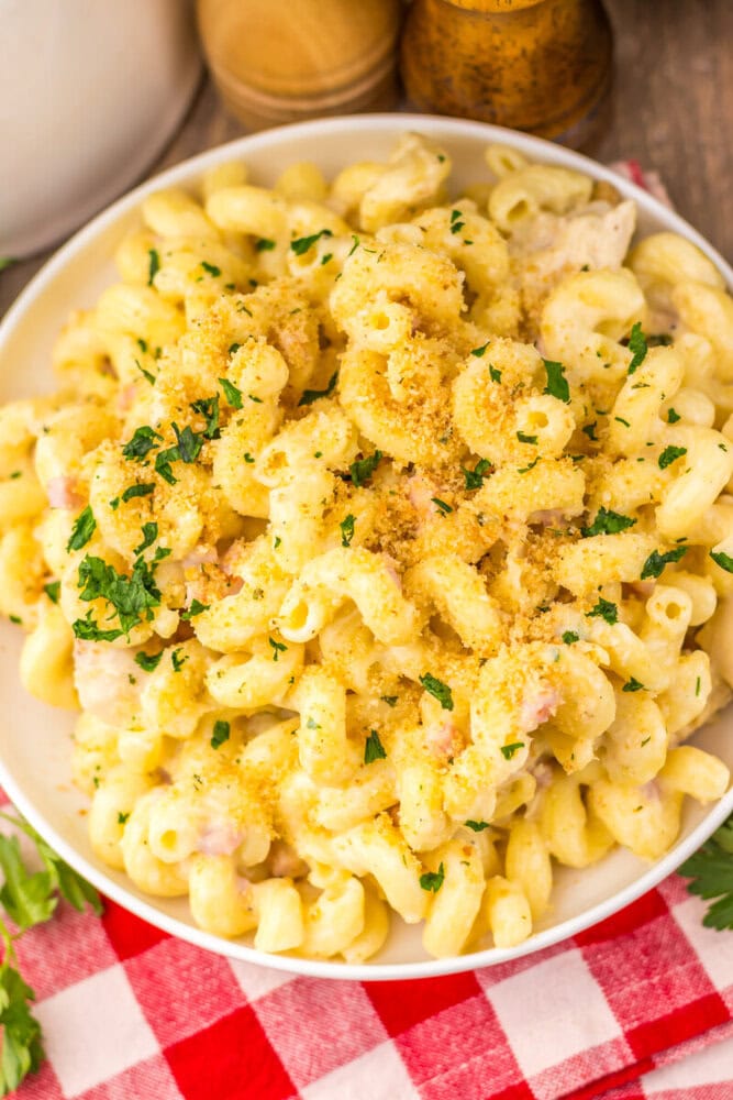 Slow cooker chicken cordon bleu pasta with creamy sauce, ham, and parsley garnish in white bowl