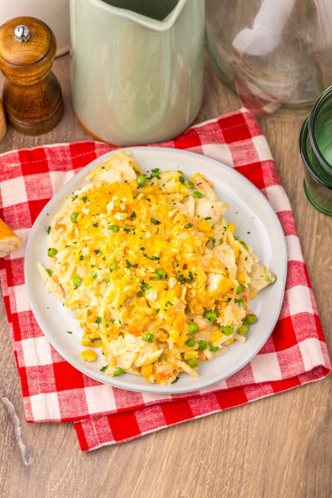 Slow cooker chicken pot pie hash brown casserole with cheddar cheese and green onion garnish on white plate