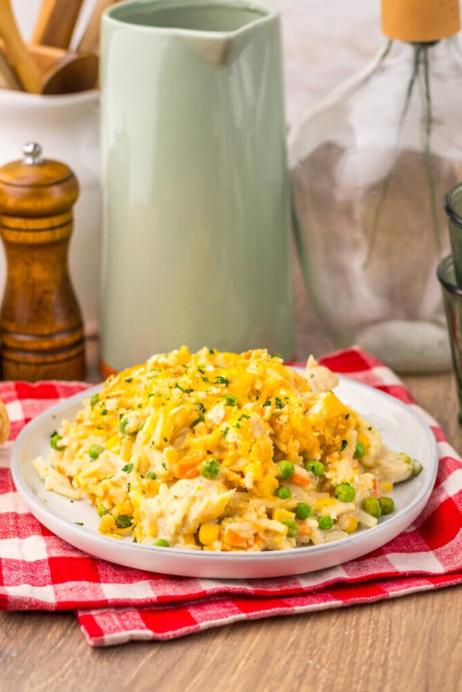 Slow cooker chicken pot pie hash brown casserole with melted cheese and peas on white plate