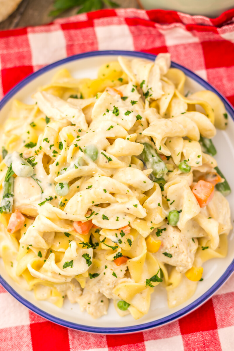 Slow cooker chicken pot pie pasta with creamy sauce, chicken, peas, carrots and corn garnished with fresh parsley