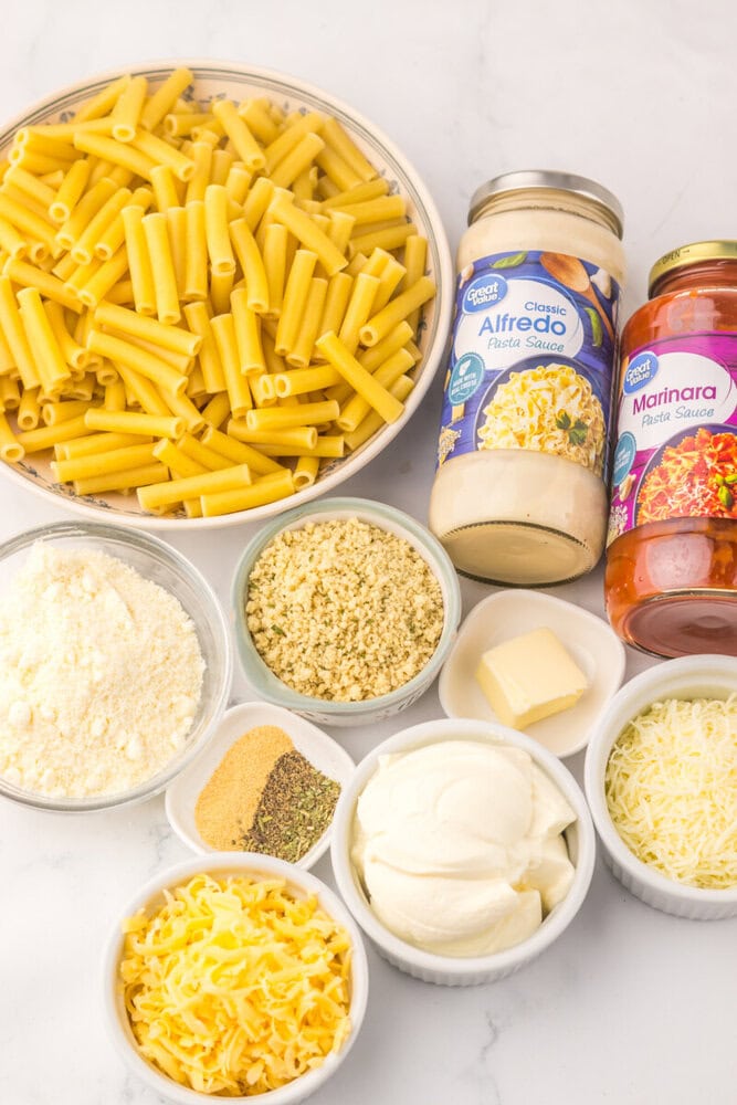 Slow cooker five cheese ziti ingredients including penne pasta, Alfredo sauce, Marinara sauce, ricotta, mozzarella, Parmesan cheese, sour cream, butter, and seasonings