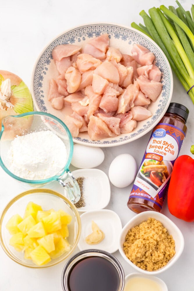 Slow cooker sweet fire chicken ingredients including diced raw chicken breast, cornstarch, eggs, pineapple, green onions, sweet chili sauce, and seasonings