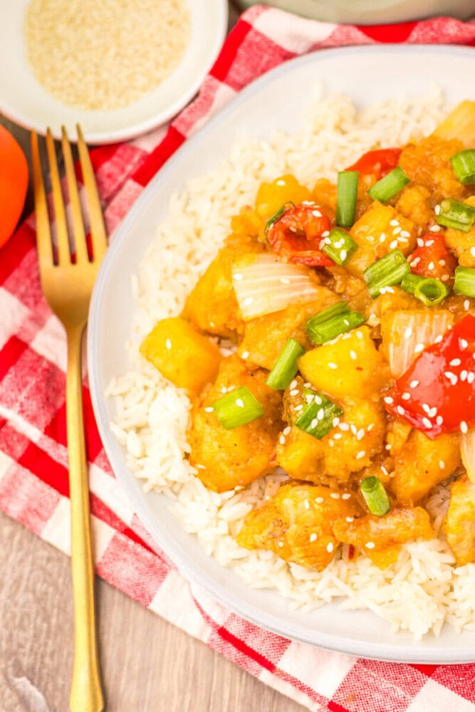 Slow cooker copycat Panda Express sweet fire chicken served over rice with sesame seeds and green onions