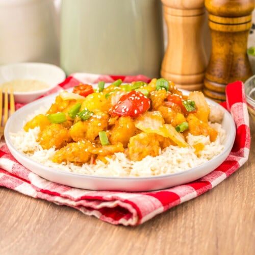 Slow Cooker Copycat Panda Express SweetFire Chicken served over rice with green onions and red peppers