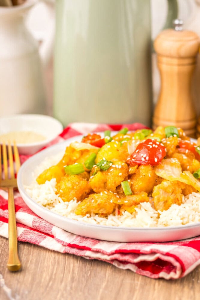 Slow cooker sweet fire chicken served over rice with sesame seeds and green onions garnish