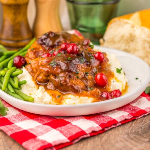 Slow cooker cranberry BBQ chicken served over mashed potatoes with green beans and pomegranate garnish