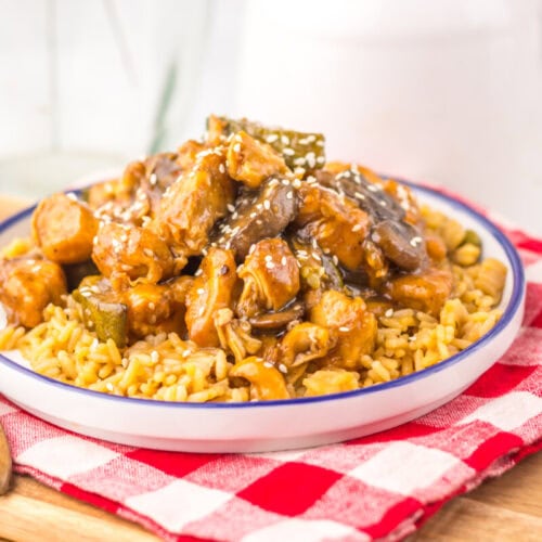 Slow cooker mushroom chicken with sesame seeds served over egg noodles on a white plate