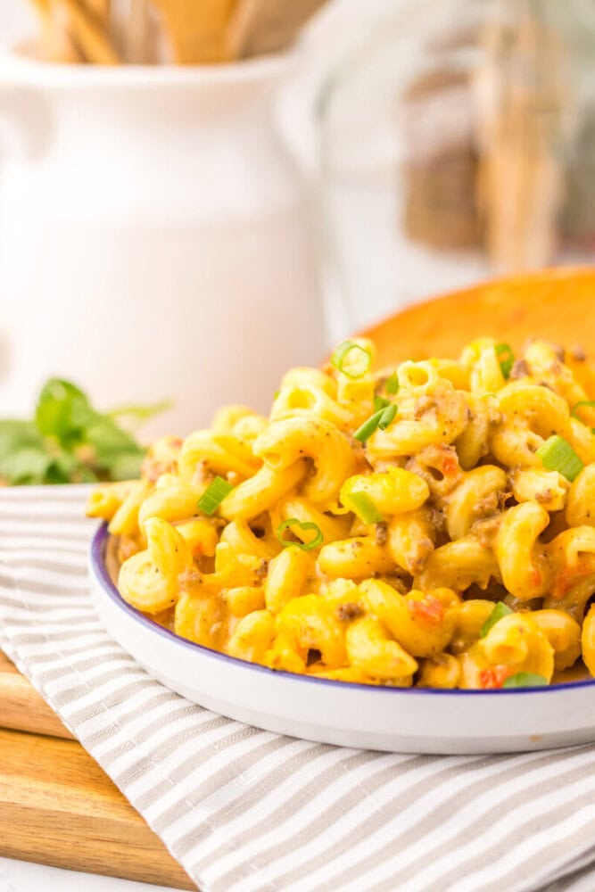 Slow cooker Rotel pasta with cheese and green onions served on a white plate