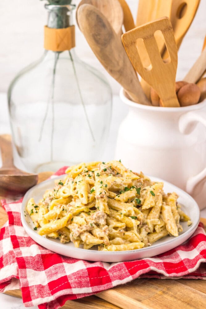 Slow cooker sausage Boursin pasta with creamy sauce and fresh herbs on white plate
