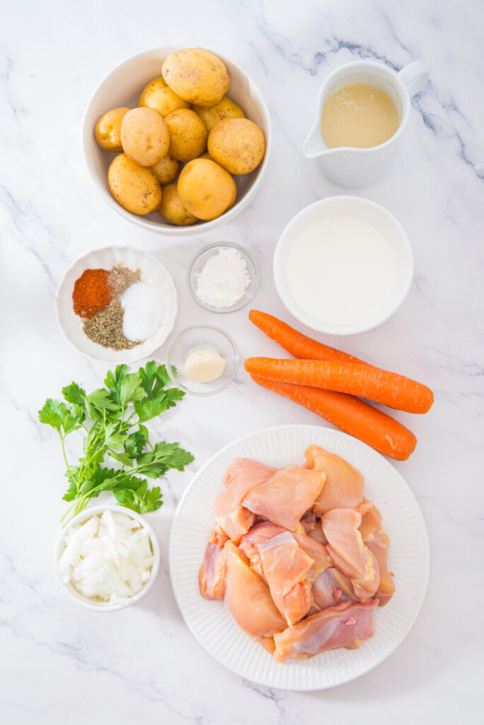Ingredients for slow cooker creamy chicken and potatoes recipe arranged on marble countertop