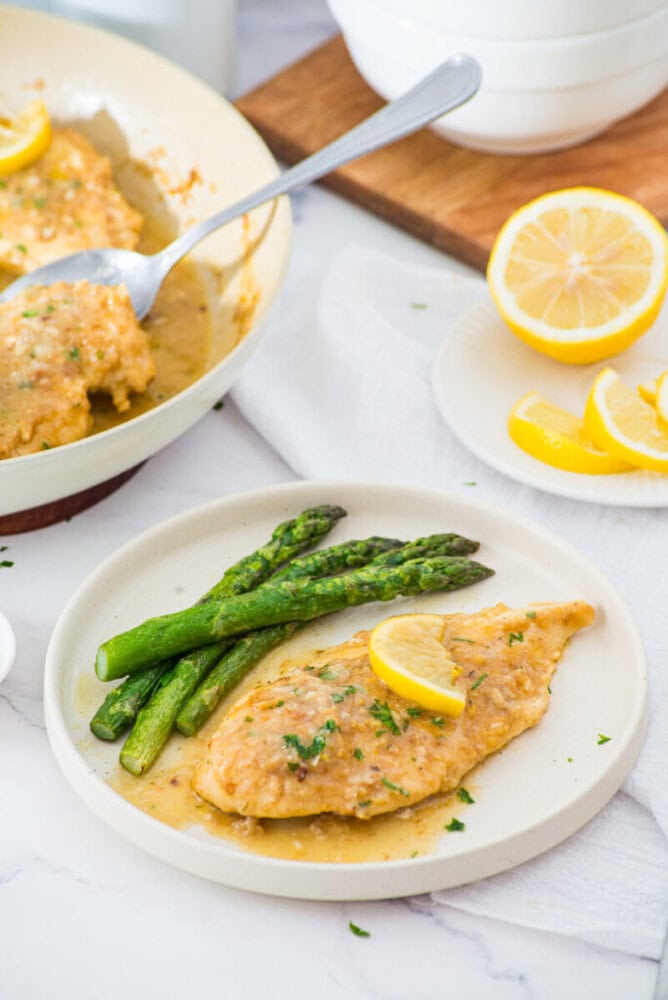 Plated lemon garlic chicken breast with asparagus and lemon sauce garnish