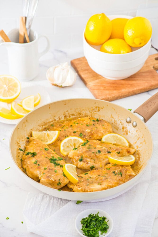 Lemon garlic chicken breast in cream sauce with lemon slices and fresh parsley in a skillet