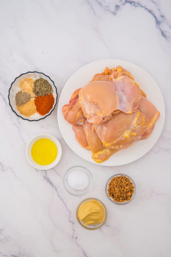 Raw chicken thighs with spice ingredients for oven baked recipe overhead view