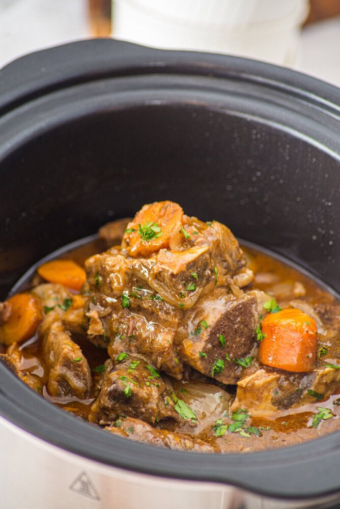 Slow cooker braised short ribs with carrots and parsley in rich gravy