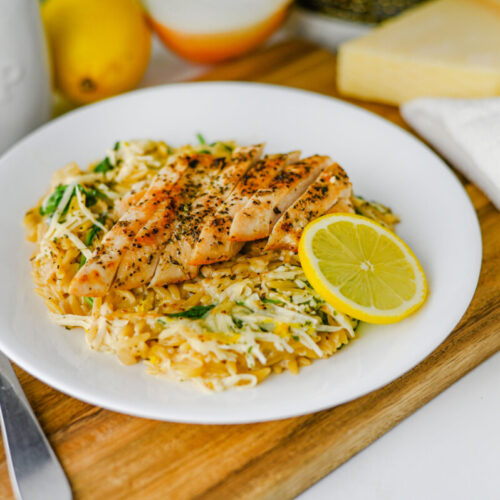 Creamy Lemon Parmesan Chicken Orzo with sliced chicken, buttered pasta, and lemon garnish plated on white dish
