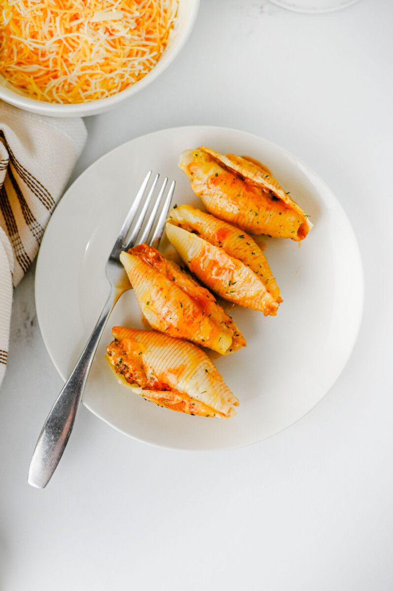 Cheesy taco stuffed shells plated and ready to serve with fork on white dish