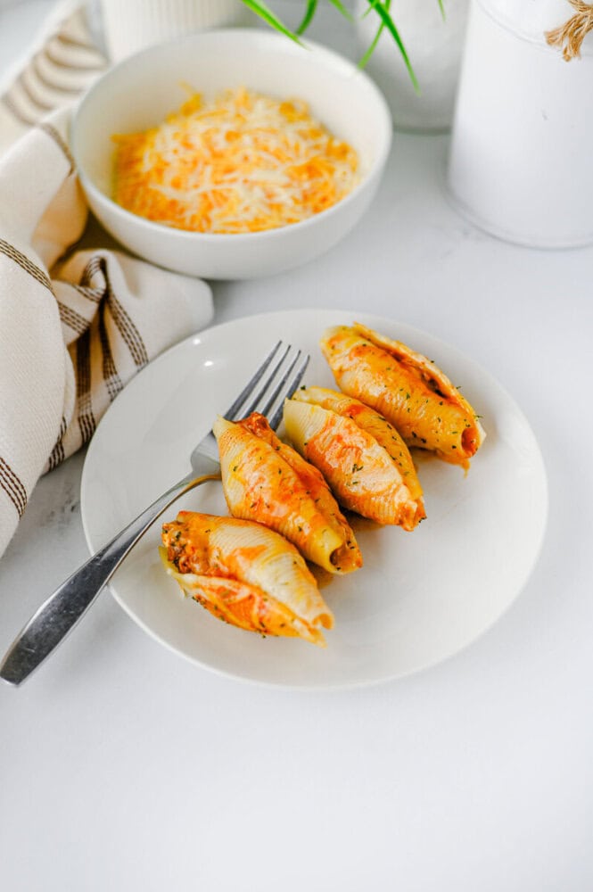 Cheesy taco stuffed shells plated with cheese sauce and fresh chives