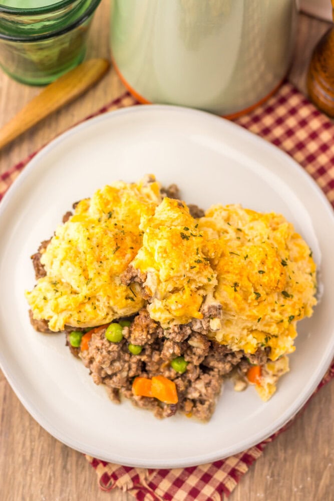 Cheddar Bay Beef Cobbler with golden biscuit topping and ground beef filling on white plate