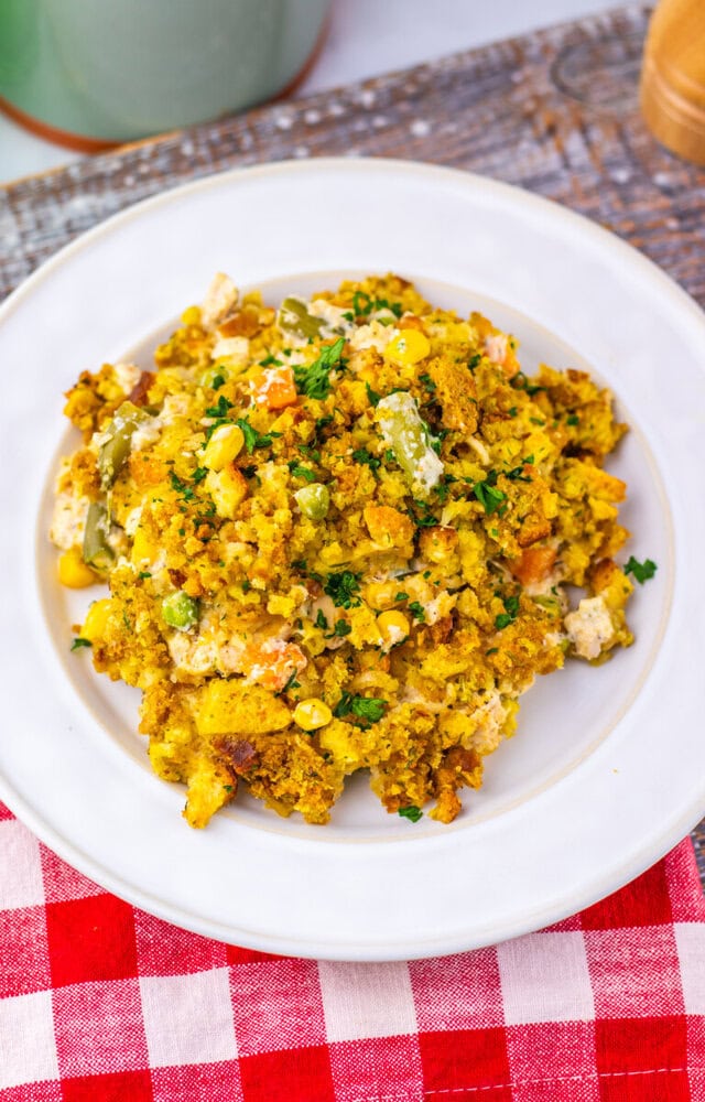 Chicken and Stuffing Pot Pie Casserole plated on white dish with corn, herbs, and golden stuffing
