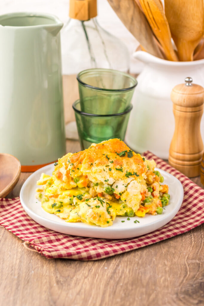 Plated scrambled eggs with corn and peas garnished with fresh herbs, served on white plate with bread and beverages