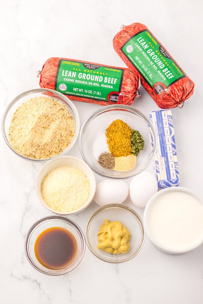 Cowboy butter meatballs ingredients including lean ground beef, breadcrumbs, spices, eggs, and condiments arranged on marble surface