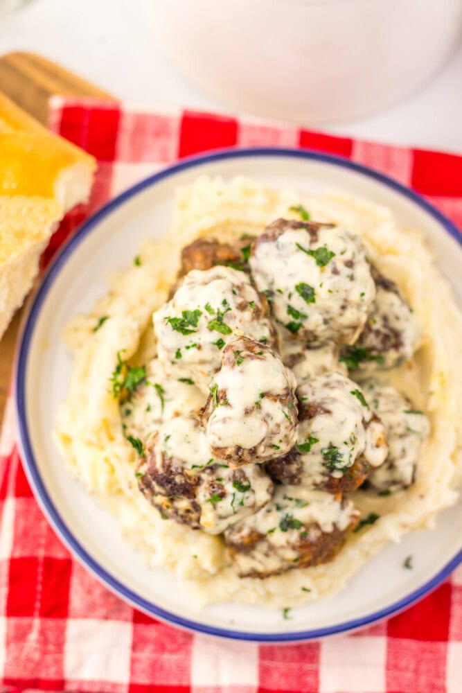 Cowboy butter meatballs with creamy mashed potatoes and fresh parsley garnish on a plated dish