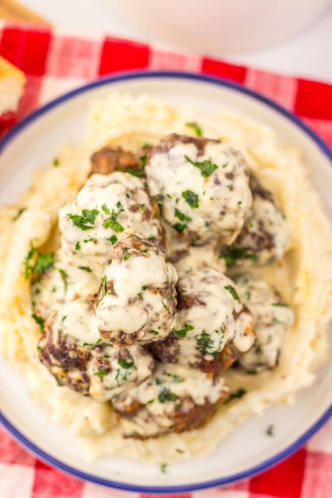 Cowboy butter meatballs with creamy sauce and parsley garnish served over mashed potatoes