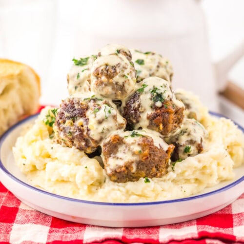 Cowboy butter meatballs with creamy mashed potatoes and fresh parsley garnish on white plate