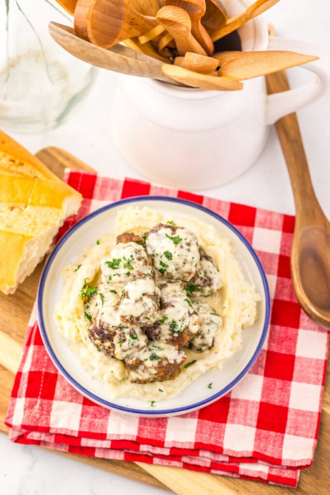 Cowboy butter meatballs with creamy sauce served over mashed potatoes, garnished with fresh parsley
