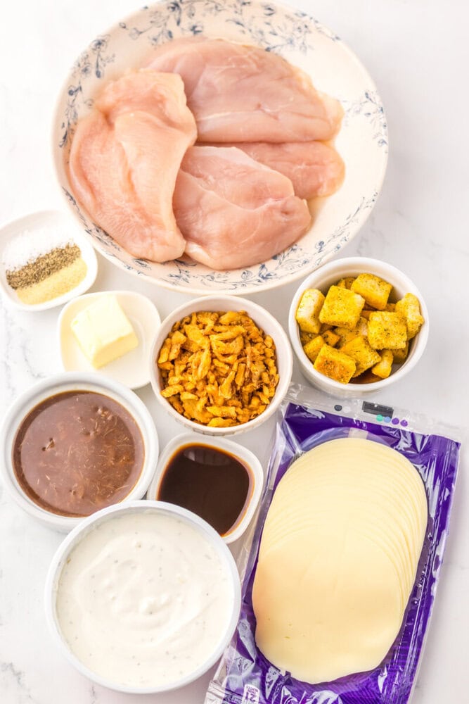 French Onion Chicken Bake ingredients laid out including raw chicken breasts, cheese slices, fried onions, butter, and sauces