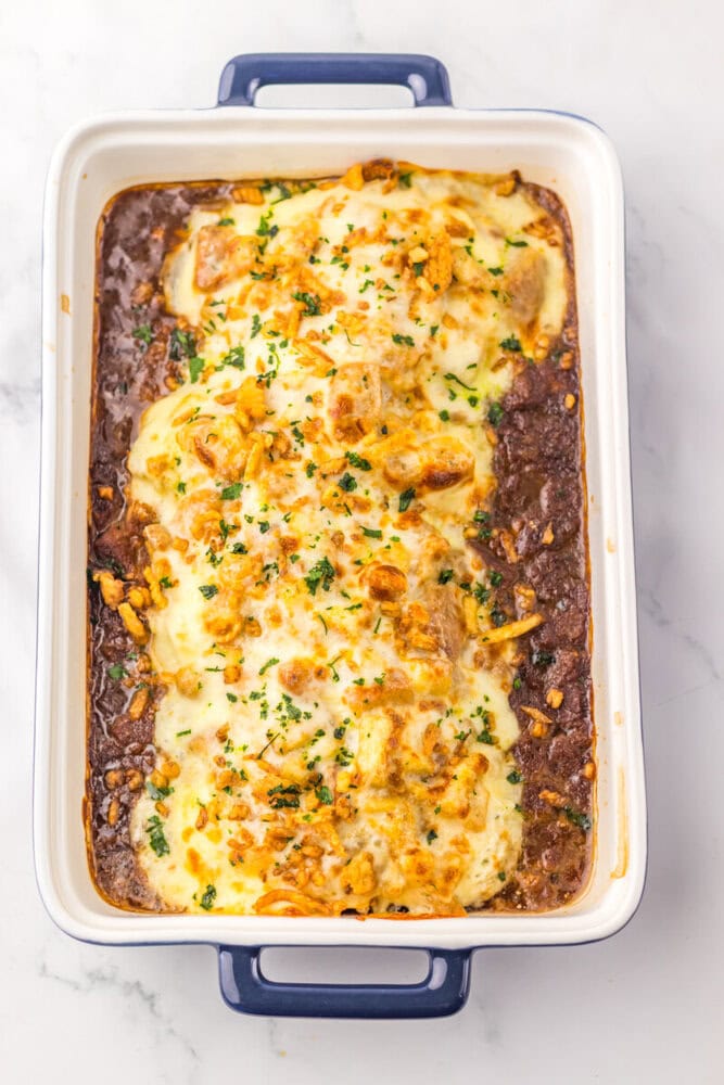 French Onion Chicken Bake with melted cheese and parsley in ceramic baking dish