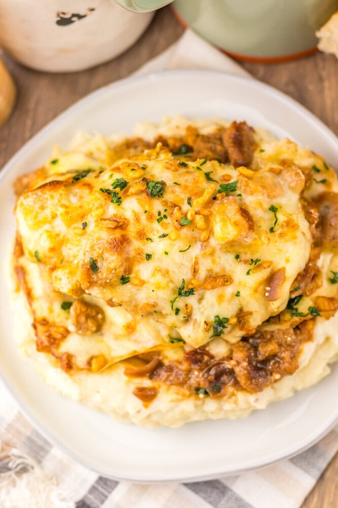 French Onion Chicken Bake with melted cheese, bacon, and caramelized onions served on mashed potatoes