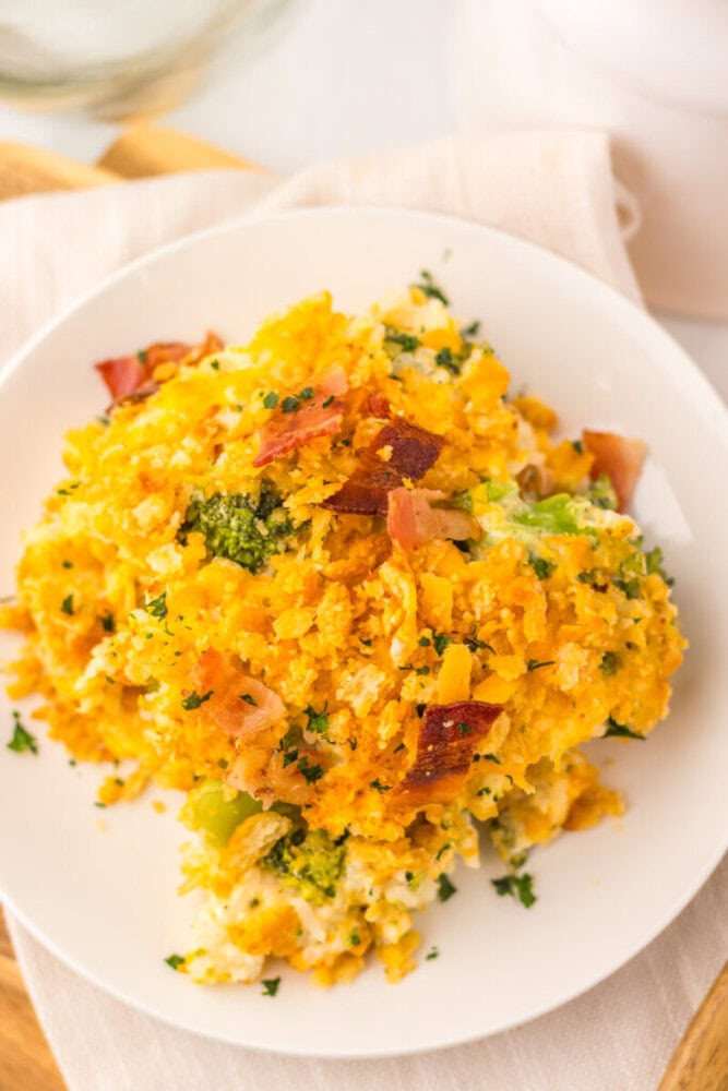 Loaded broccoli rice casserole served on white plate with bacon and parsley garnish