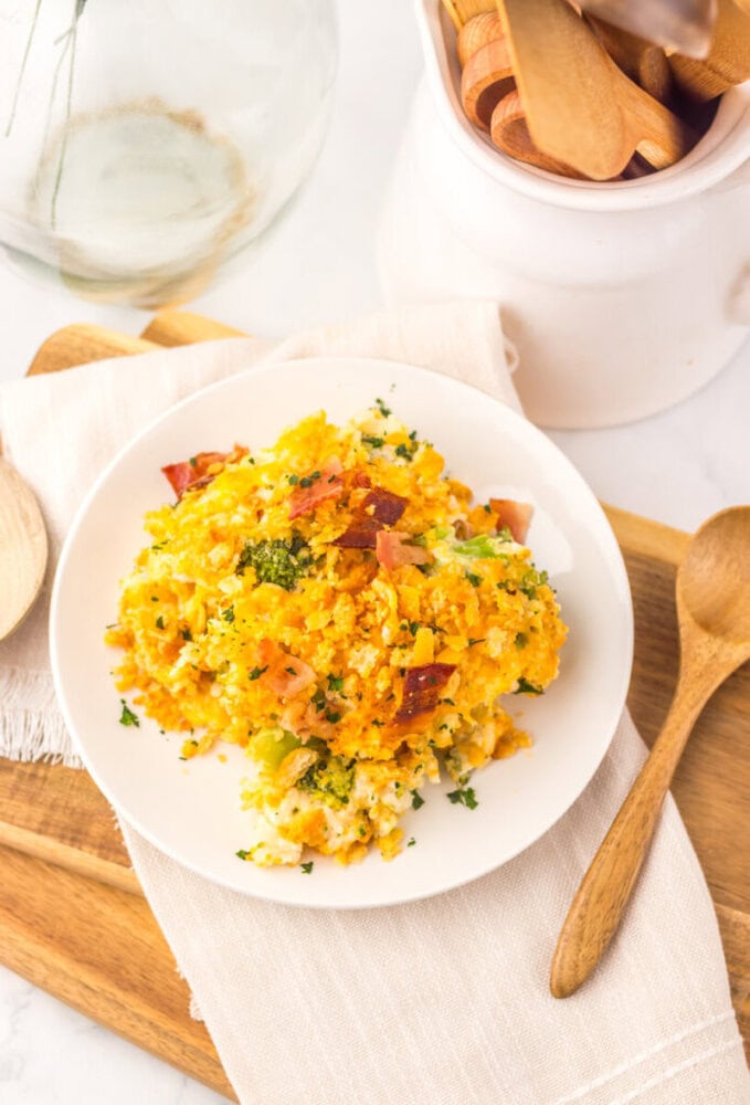 Loaded broccoli rice casserole plated on white dish with bacon and fresh herbs garnish