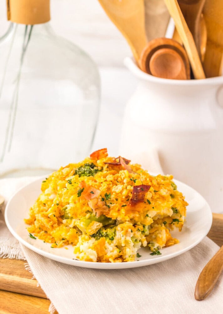 Loaded broccoli rice casserole plated on white dish with fresh herbs and bacon garnish
