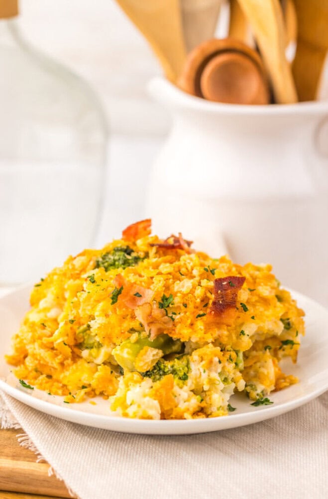 Loaded broccoli rice casserole served on white plate with herb garnish and bacon