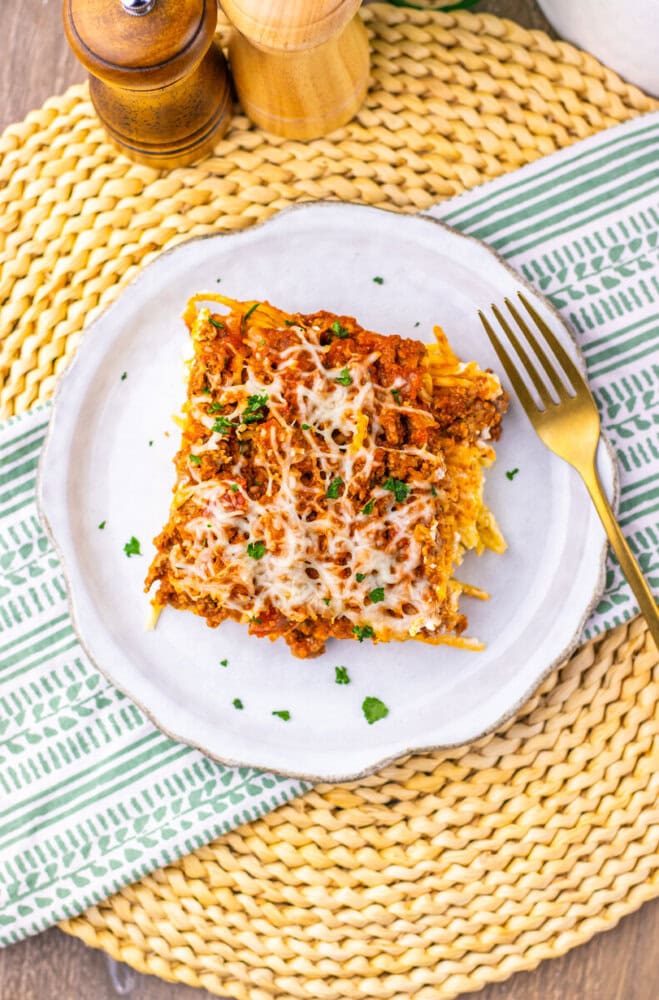 Million Dollar Spaghetti Casserole plated on white dish with melted cheese and parsley garnish
