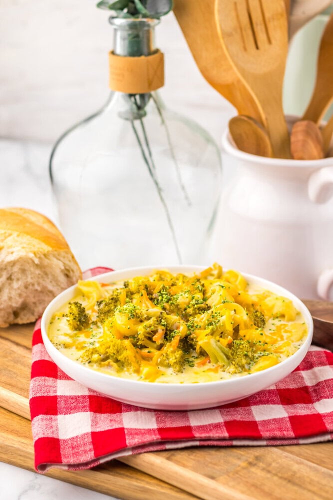 Slow cooker broccoli cheddar tortellini soup plated in white bowl with herb garnish