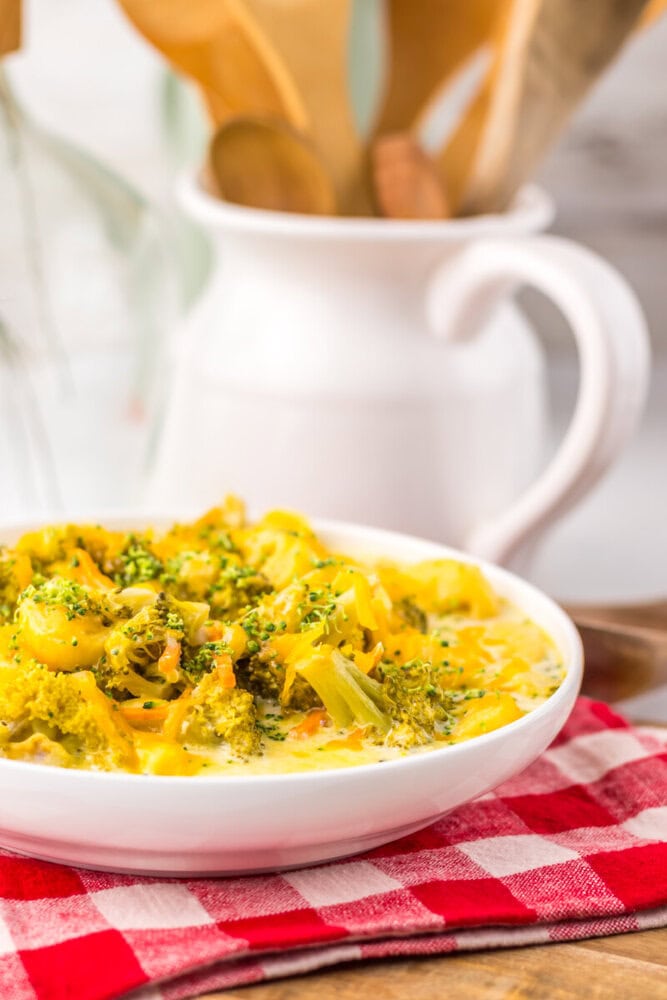 Bowl of slow cooker broccoli cheddar tortellini soup with fresh herb garnish served on white plate