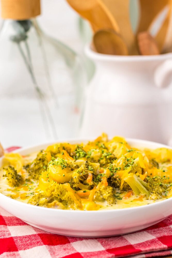 Bowl of slow cooker broccoli cheddar tortellini soup with green herb garnish served on white plate
