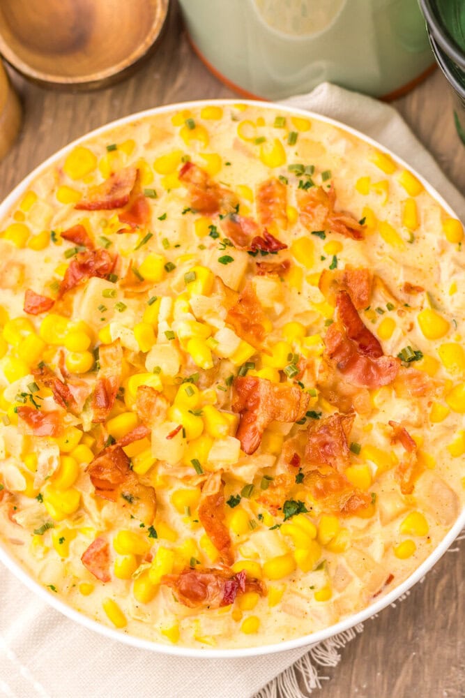 Slow cooker creamy bacon corn chowder in white bowl topped with bacon bits and chives