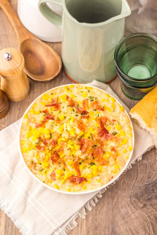 Slow cooker creamy bacon corn chowder in white bowl with bacon bits and corn garnish