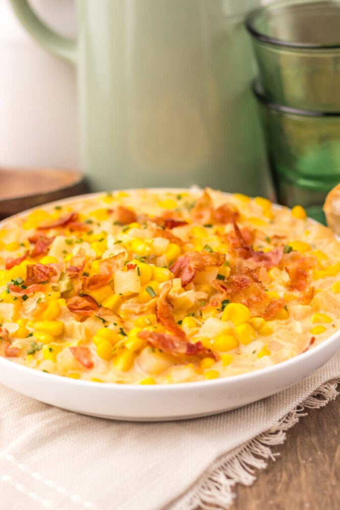Slow cooker creamy bacon corn chowder in white bowl with bacon and corn garnish