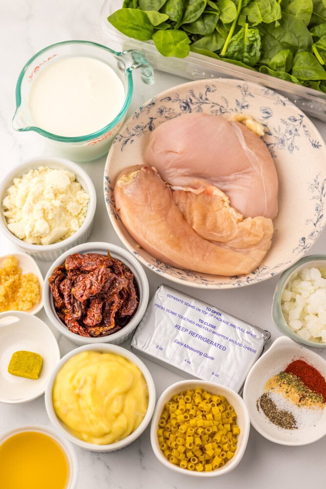 Slow Cooker Marry Me Chicken Soup ingredients laid out including raw chicken, cream, mayo, corn, onions, and spinach