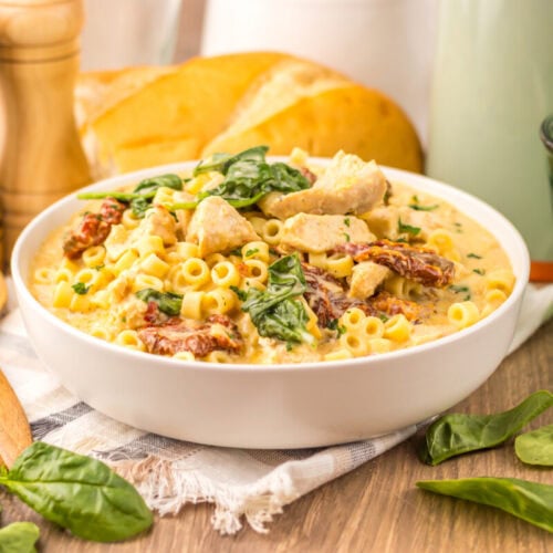 Slow cooker marry me chicken soup with pasta, bacon, spinach and creamy sauce in white bowl