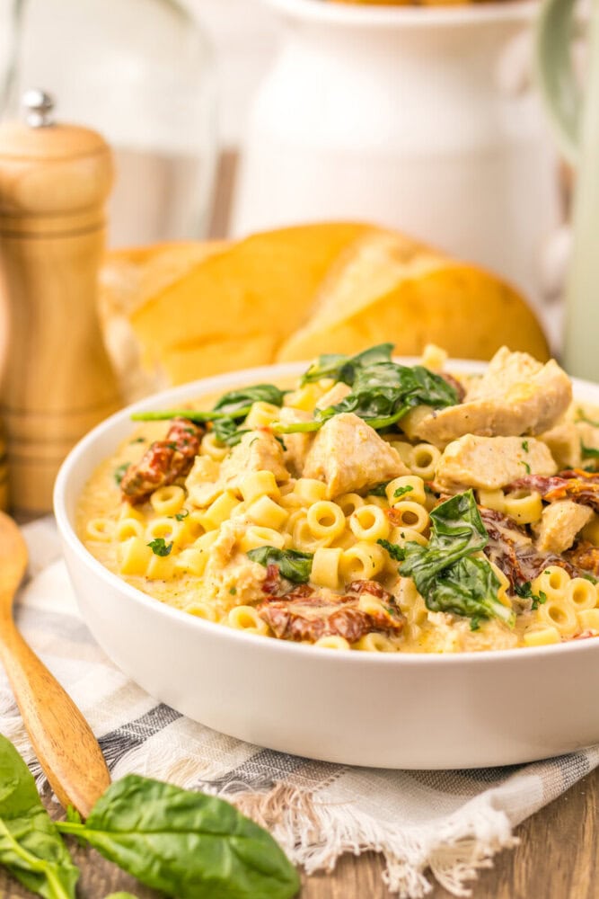 Slow cooker marry me chicken soup with pasta, chicken, and basil in white bowl
