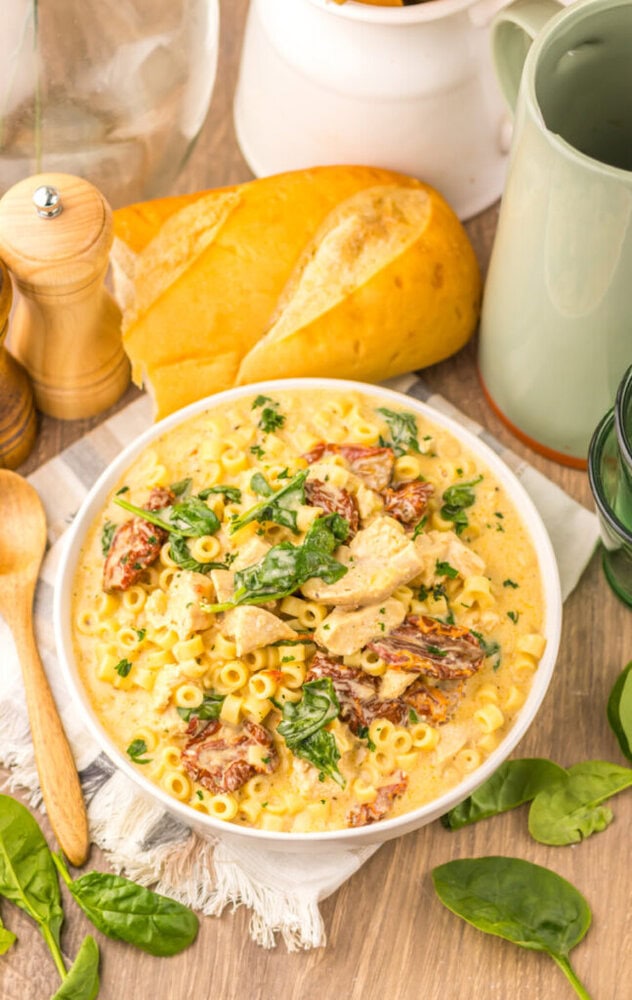 Slow Cooker Marry Me Chicken Soup with pasta, bacon, and fresh basil in white bowl with crusty bread