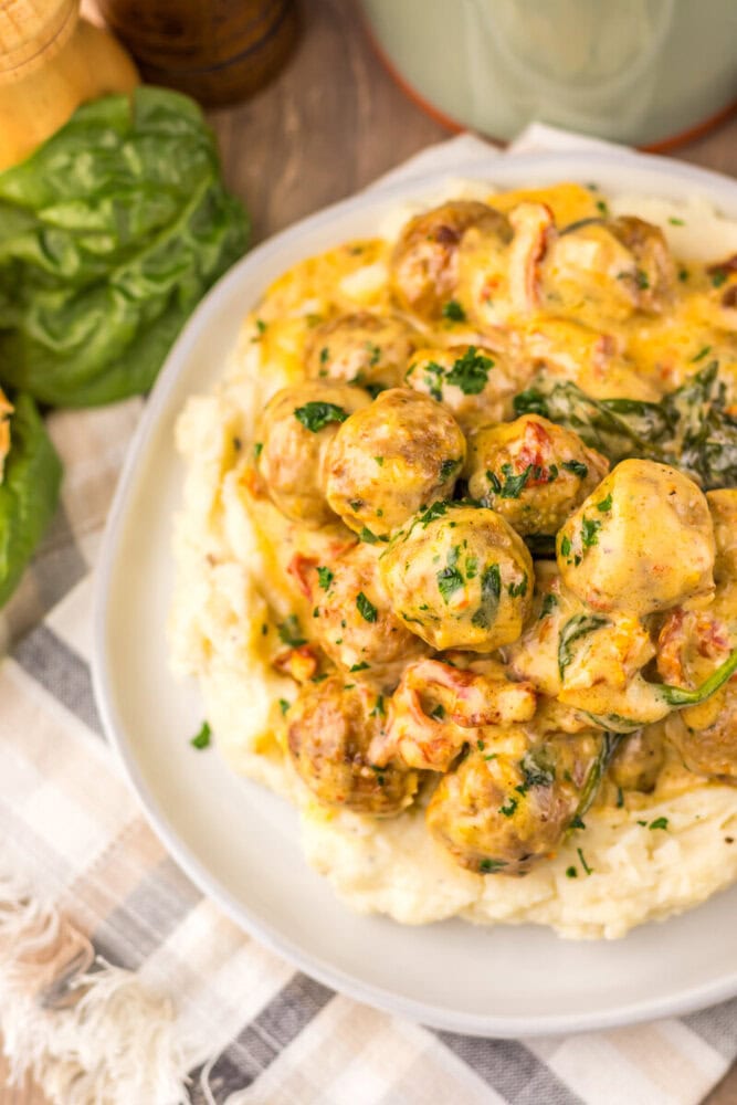 Slow cooker creamy marry me meatballs over mashed potatoes garnished with parsley