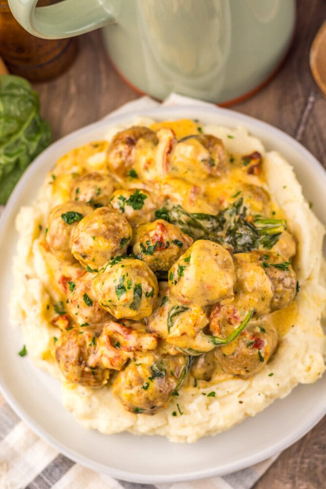 Slow cooker creamy marry me meatballs with spinach served over mashed potatoes